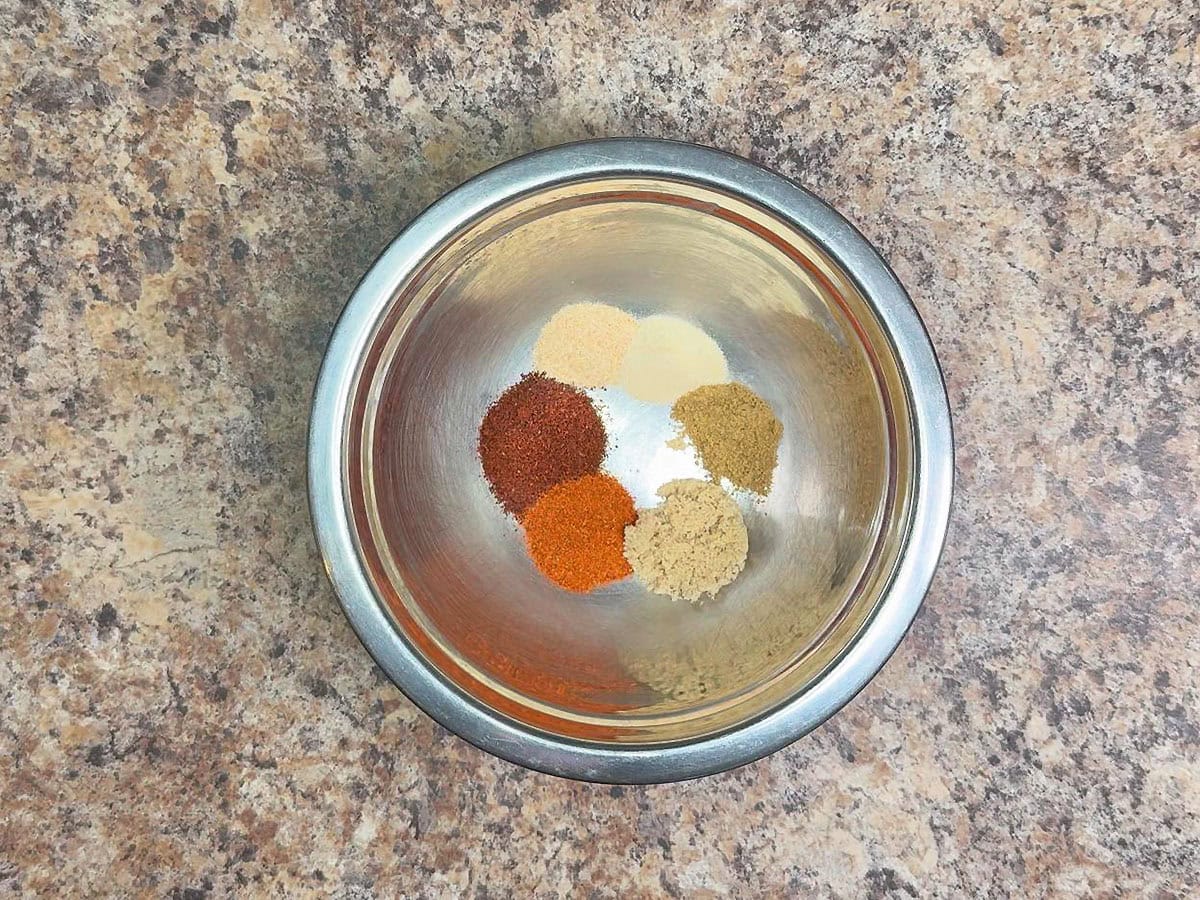 Chili powder, paprika, garlic powder, onion powder, cumin, and brown sugar in a small mixing bowl.
