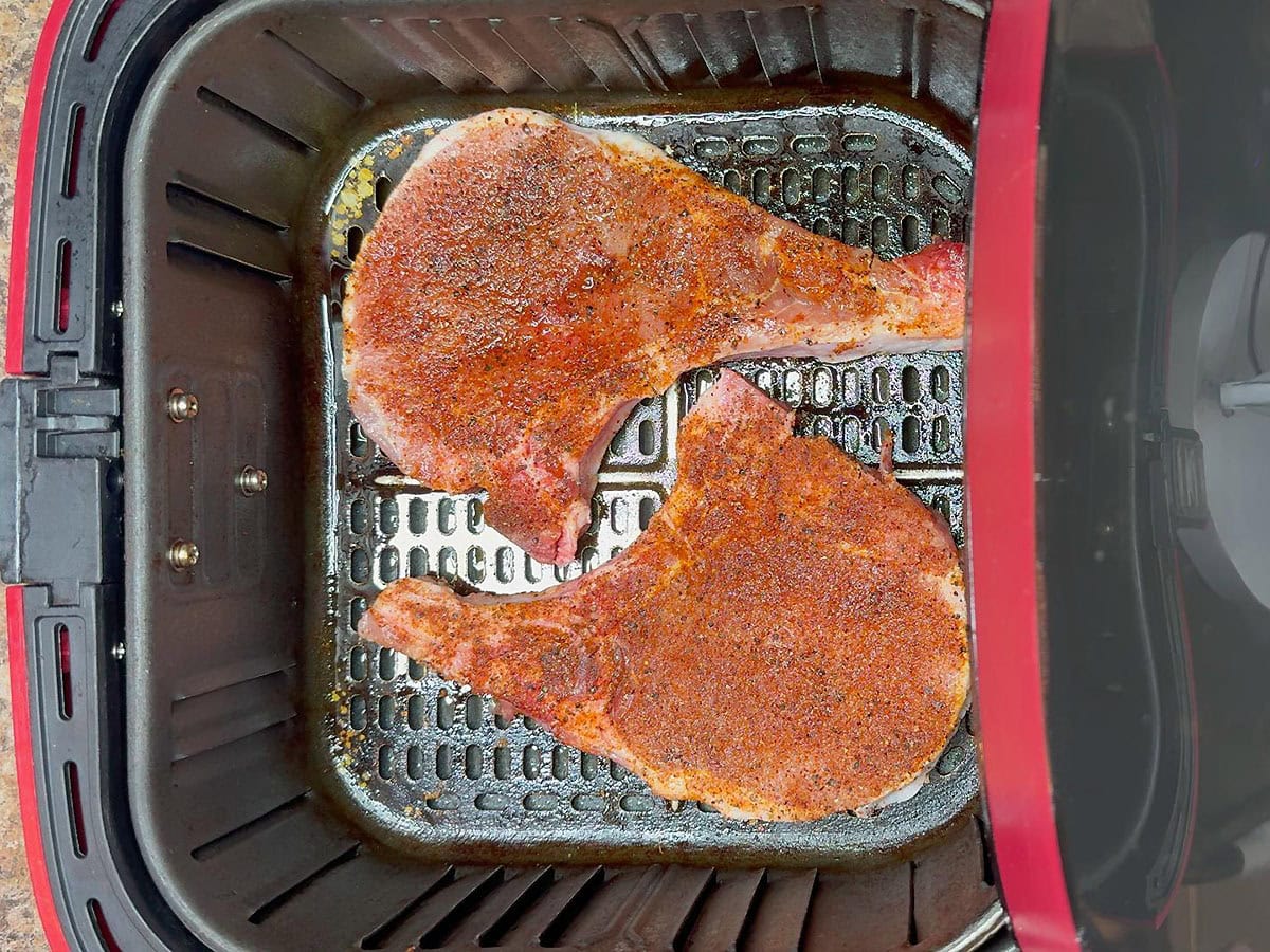 Placing the pork chops in the preheated air fryer.