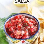 Fresh garden salsa in a decorative bowl, surrounded by tortilla chips and two bottles of Mexican beer in the background.