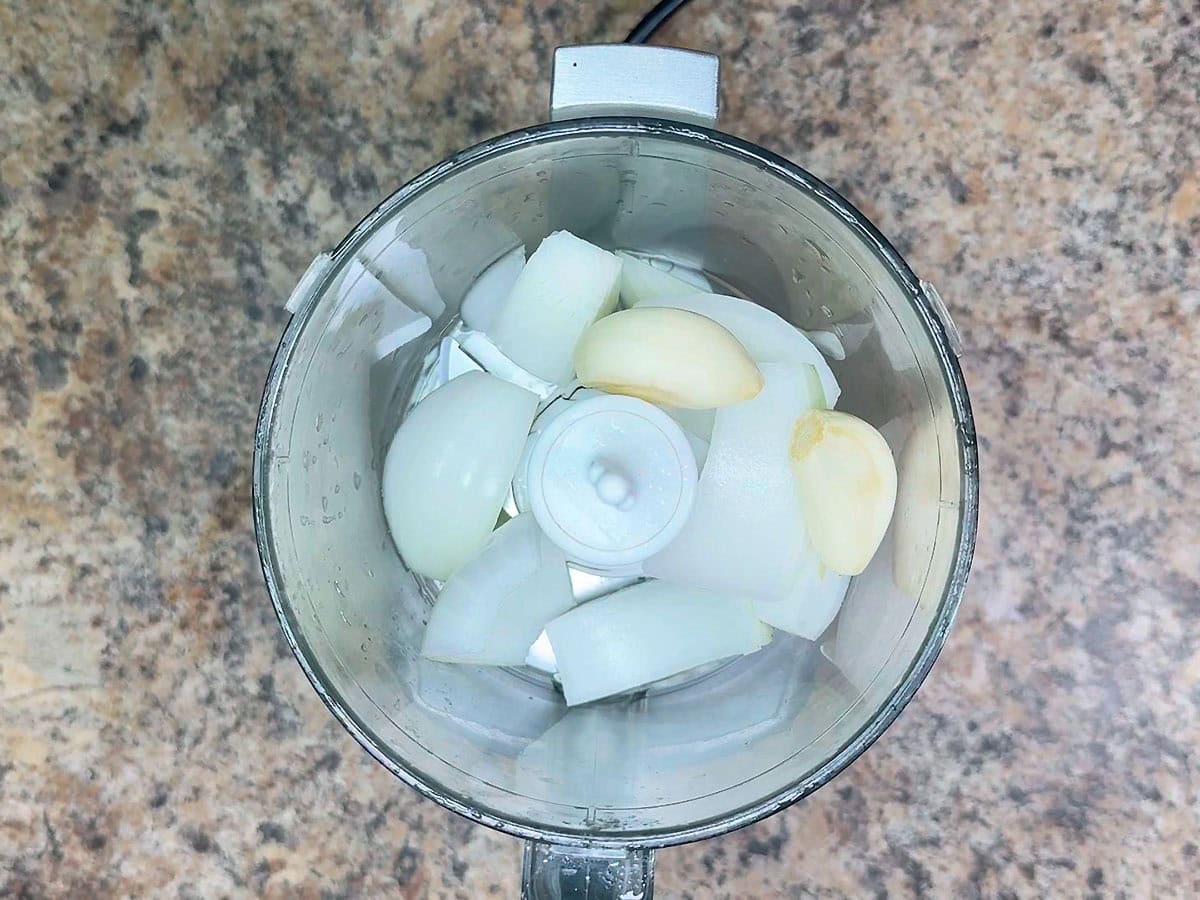 Quartered onion and whole garlic cloves in a food processor.