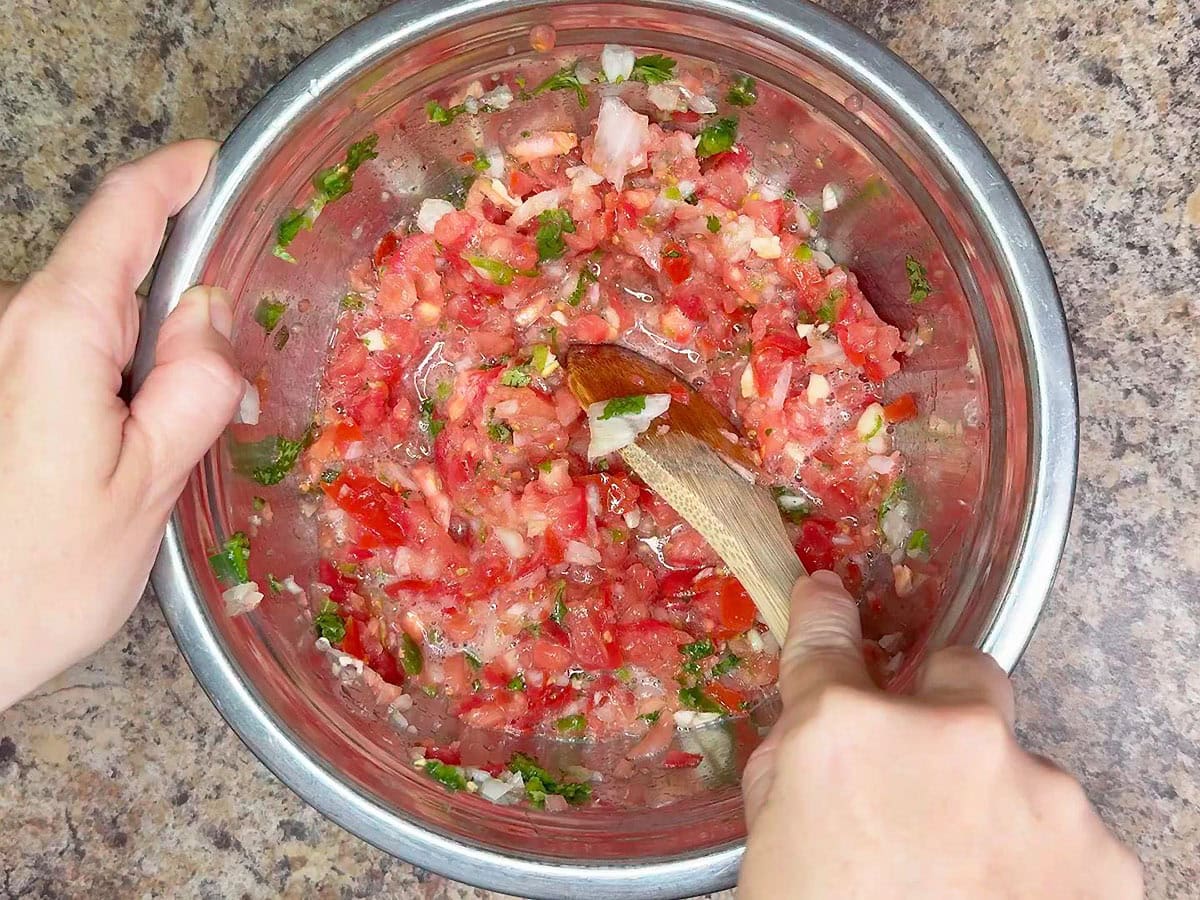 Stirring the chopped salsa vegetables with the sugar, salt and vinegar.