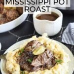 Instant Pot Mississippi Pot Roast served over a bed of mashed potatoes and gravy. A gravy boat, serving dish with roast, a small dish of peppers and an Instant Pot are seen in the background.