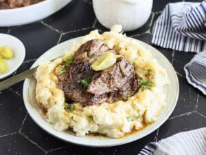Instant Pot Mississippi Pot Roast served over a bed of mashed potatoes and gravy.