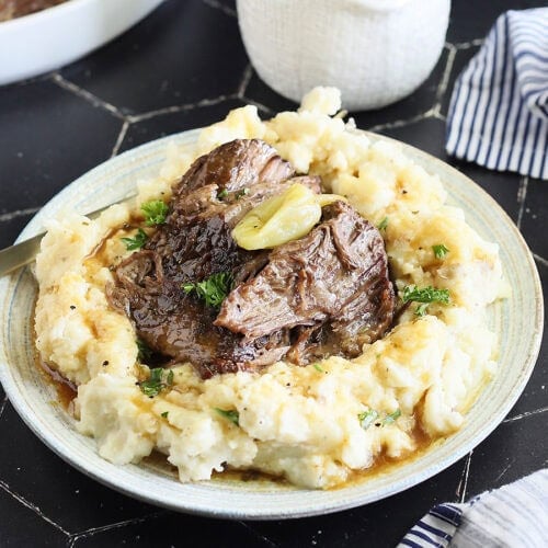 Instant Pot Mississippi Pot Roast served over a bed of mashed potatoes and gravy.