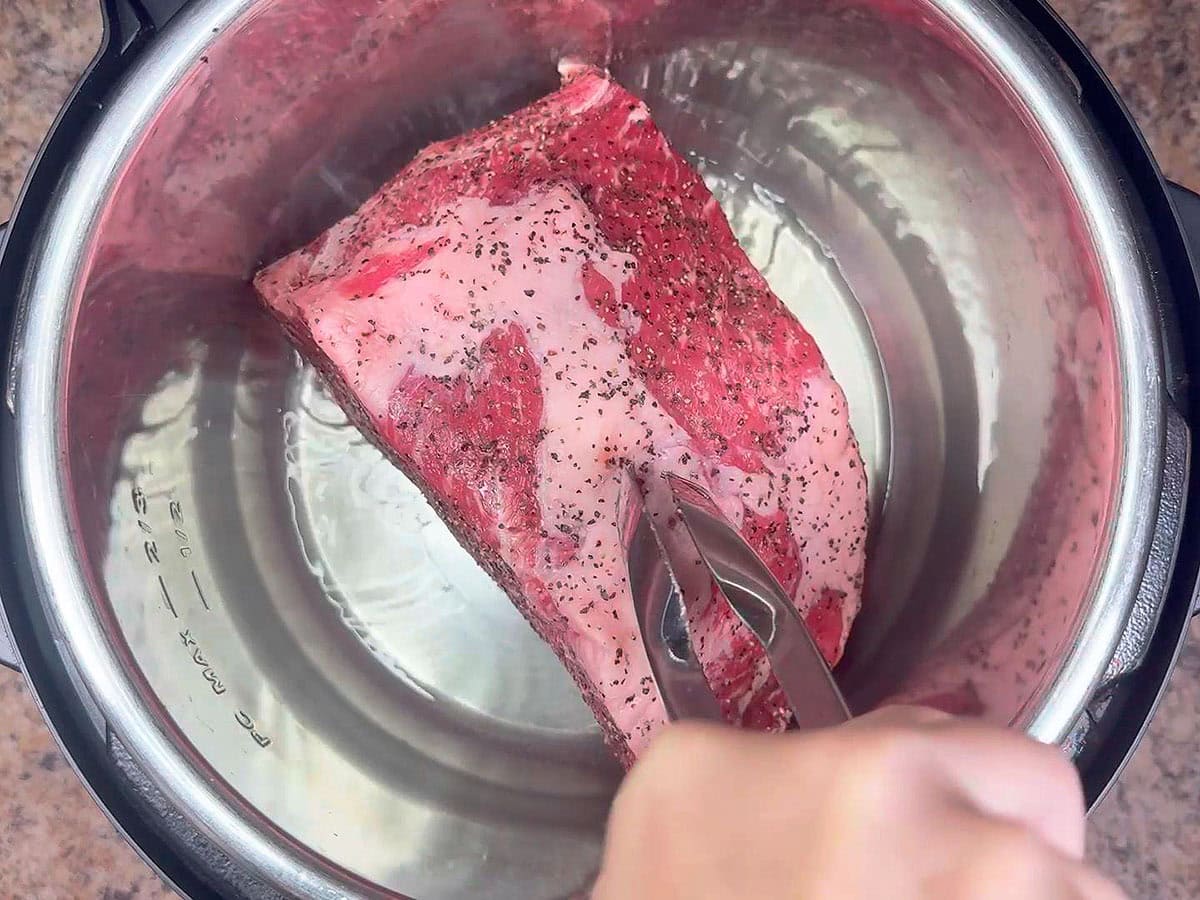 Searing all sides of a chuck roast in oil in an Instant Pot.
