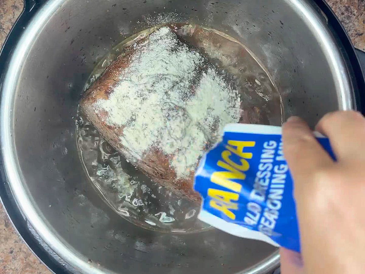 Sprinkling the Ranch seasoning mix over the roast in the Instant Pot.