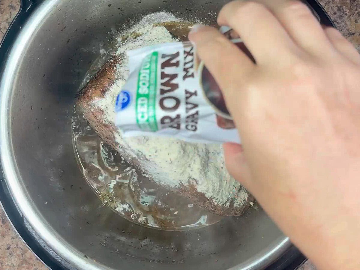 Sprinkling brown gravy mix over the roast in the Instant Pot.