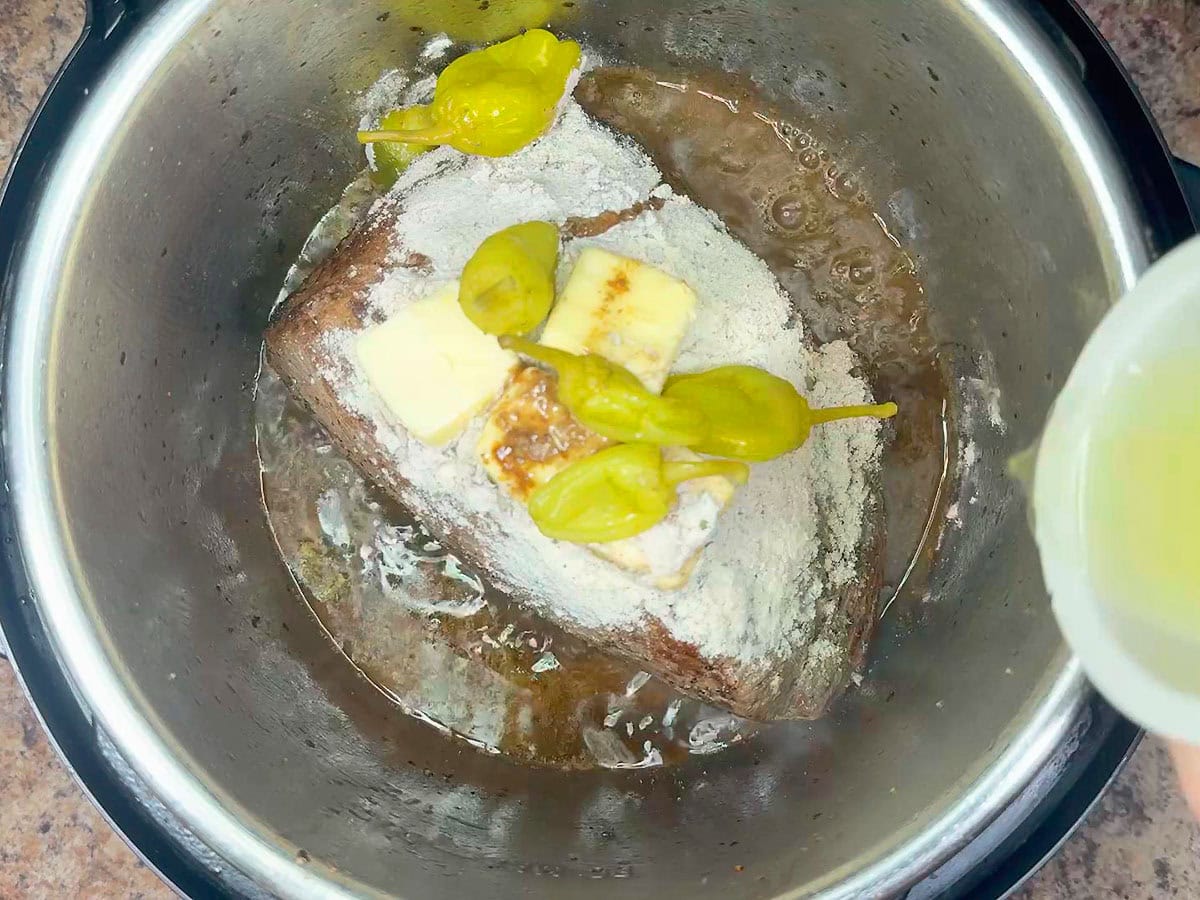Pouring the pepper juice from the jar into the Instant Pot.