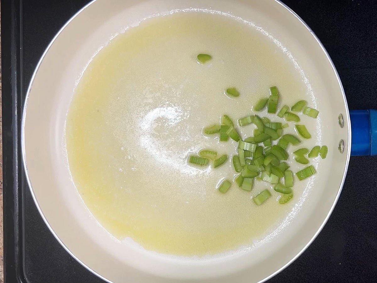 Diced celery in a skillet with melted butter.