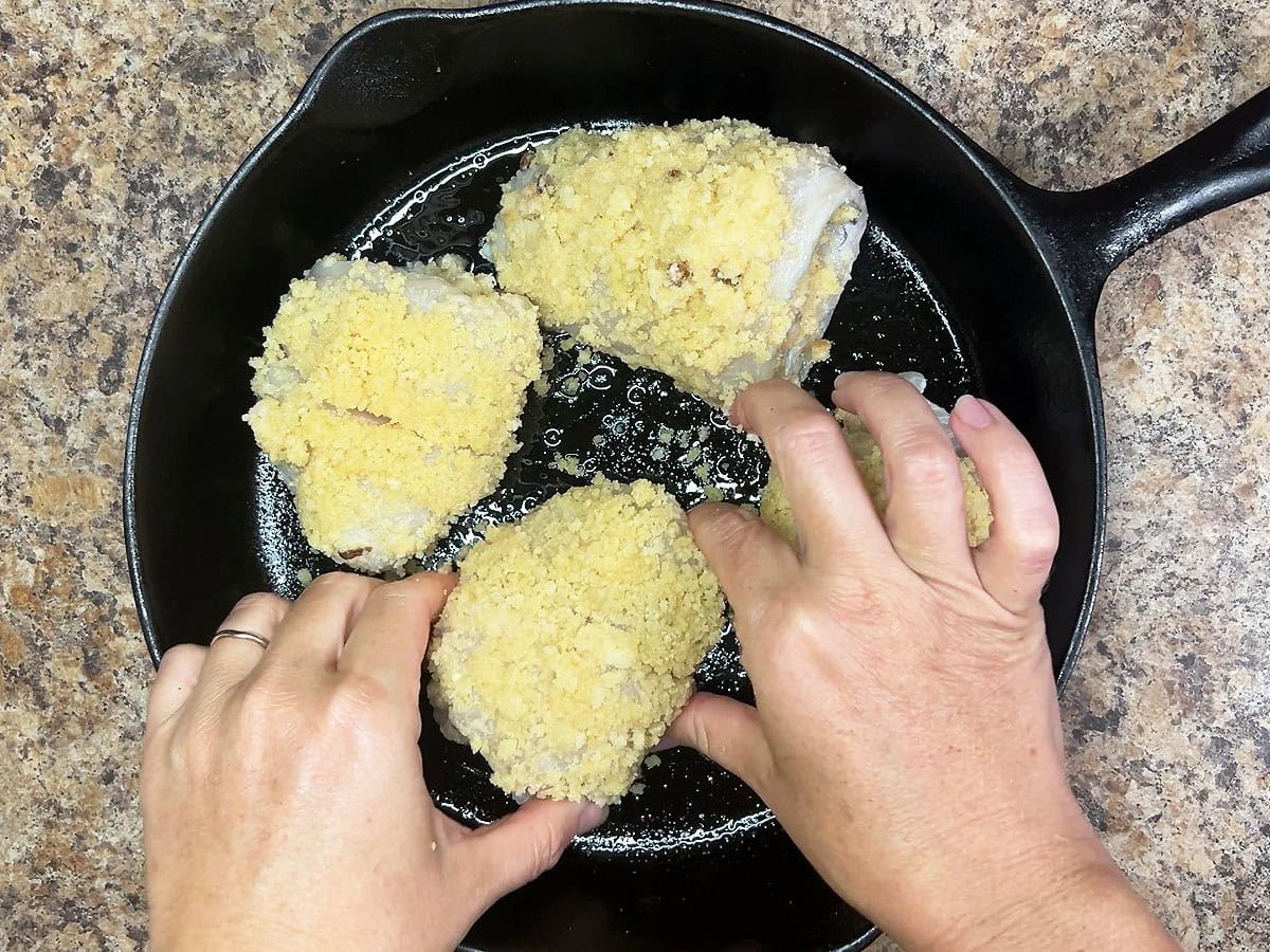 Placing the bread crumb coated fish fillets in a skillet.