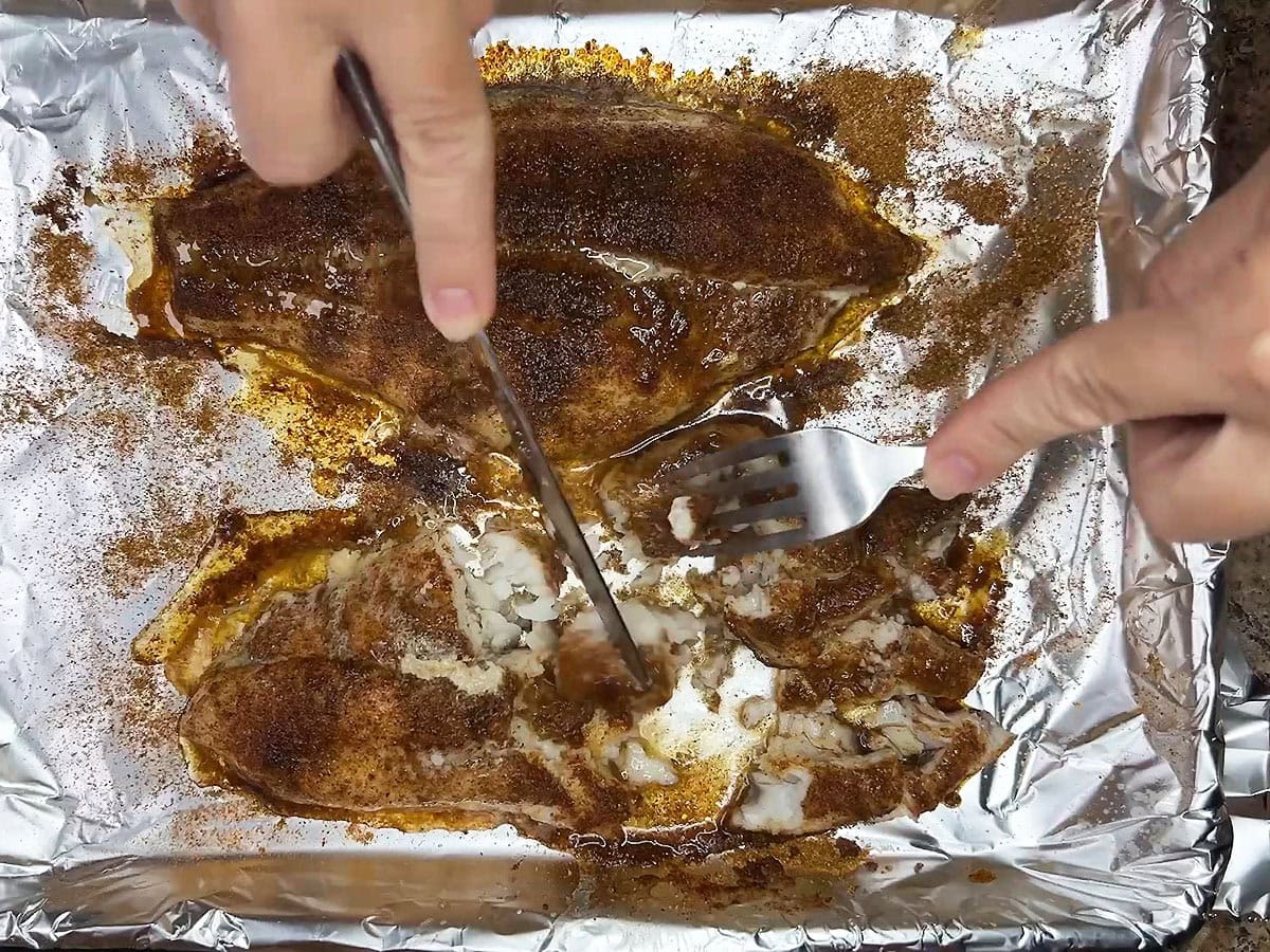 Cutting the cooked catfish into bite-sized pieces.
