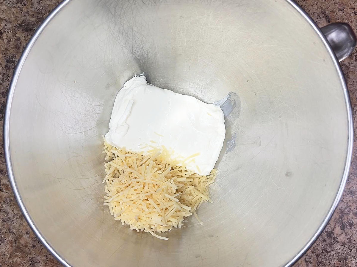 Eight ounces of cream cheese and ¾ cup of shredded Parmesan cheese in a mixing bowl.