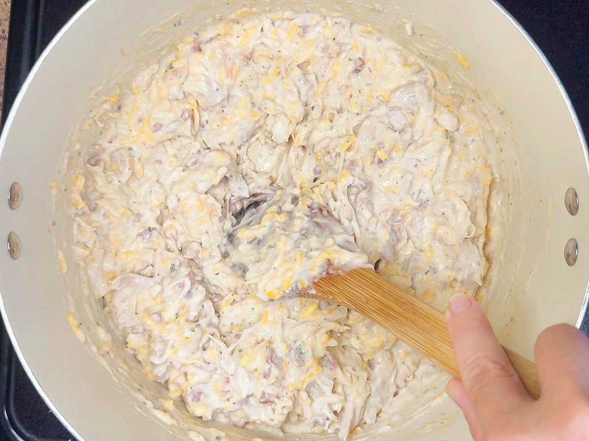 Stirring the chicken mixture until the ingredients are evenly mixed.