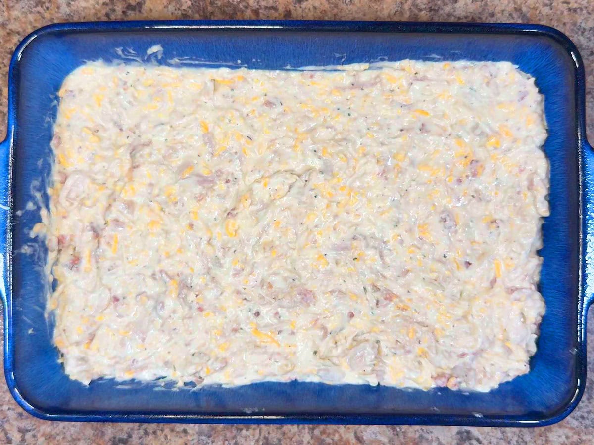 The chicken mixture spread into the bottom of a greased rectangular casserole dish.