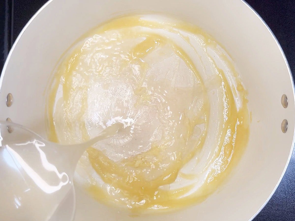 Pouring chicken broth into the flour and butter mixture.
