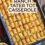 Bacon chicken ranch tater tot casserole garnished with sliced green onions, with small dishes of additional green onions, bacon bits and shredded cheese on the side.
