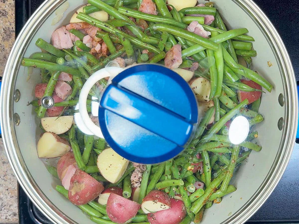 Bringing the green beans and potatoes to a simmer, then covering the pot with a lid.