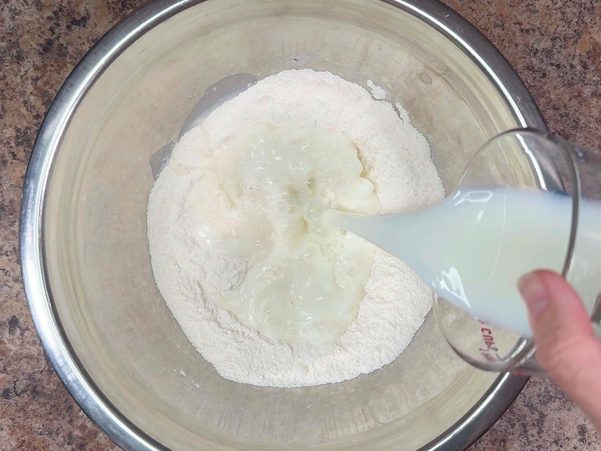 Adding milk to the dry ingredients for the mini corndog batter.