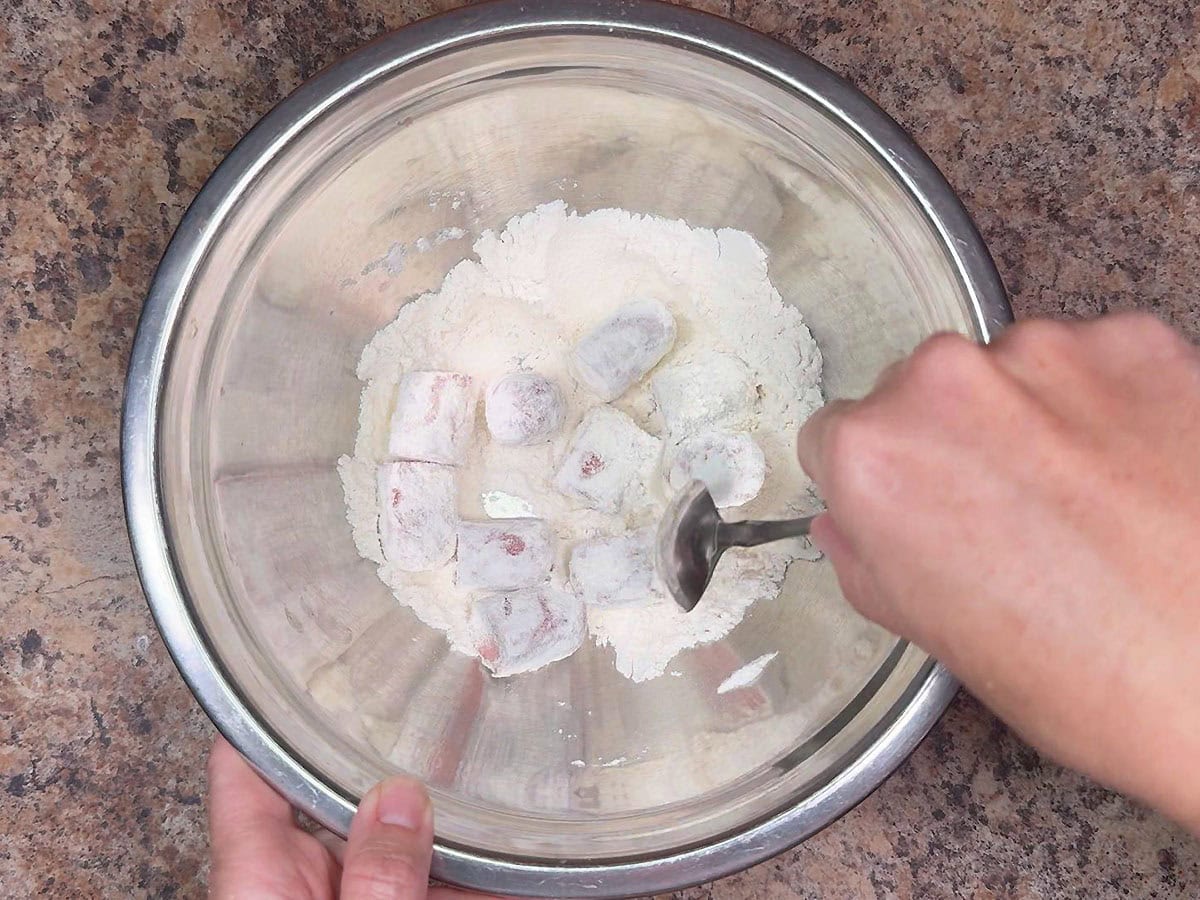 Coating the hot dog pieces in flour.