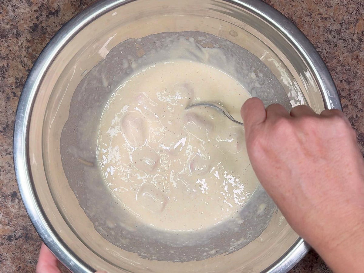 Coating the flour coated hot dog pieces with the corn dog batter.