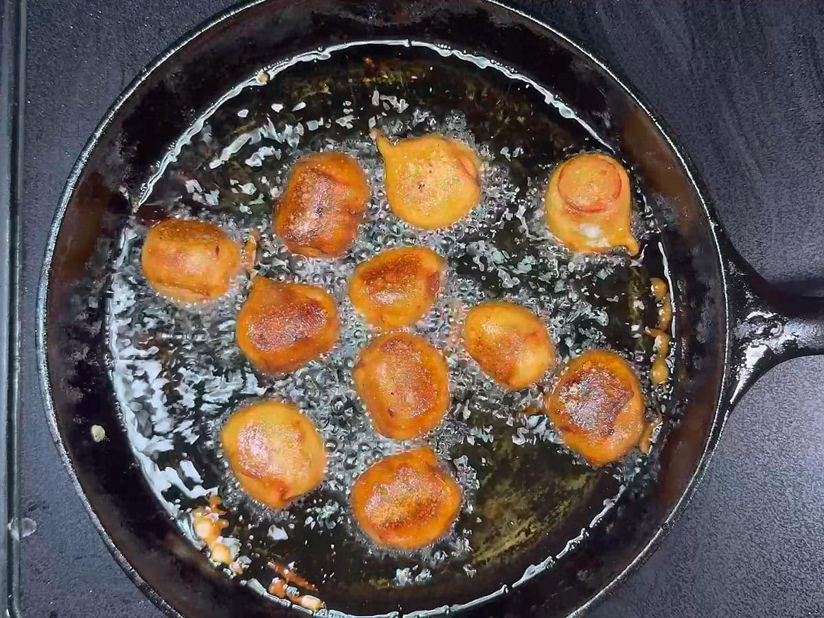 Browned mini corn dog bites frying in the hot oil.