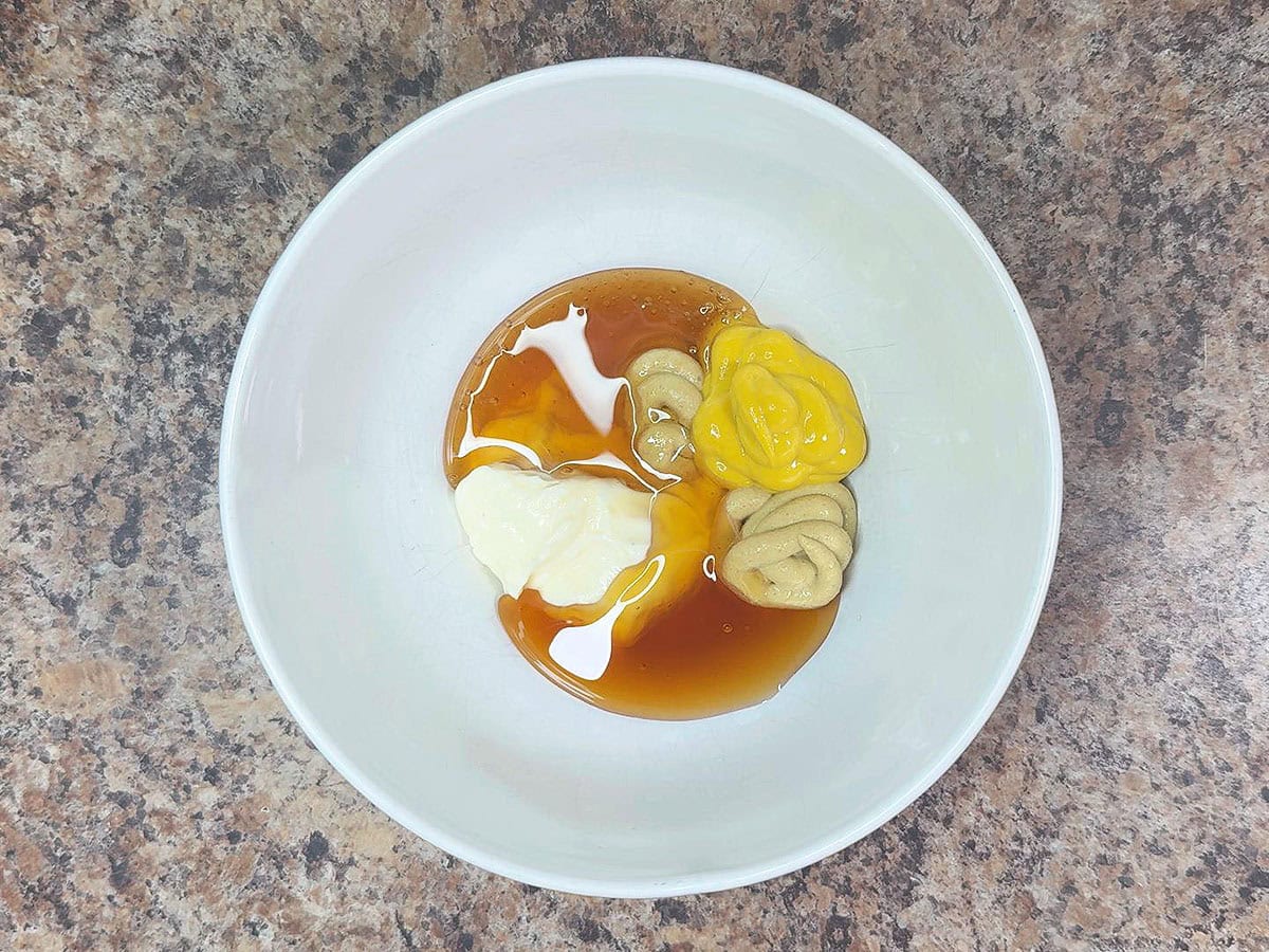 Mayonnaise, Dijon mustard, yellow mustard, and honey in a mixing bowl.