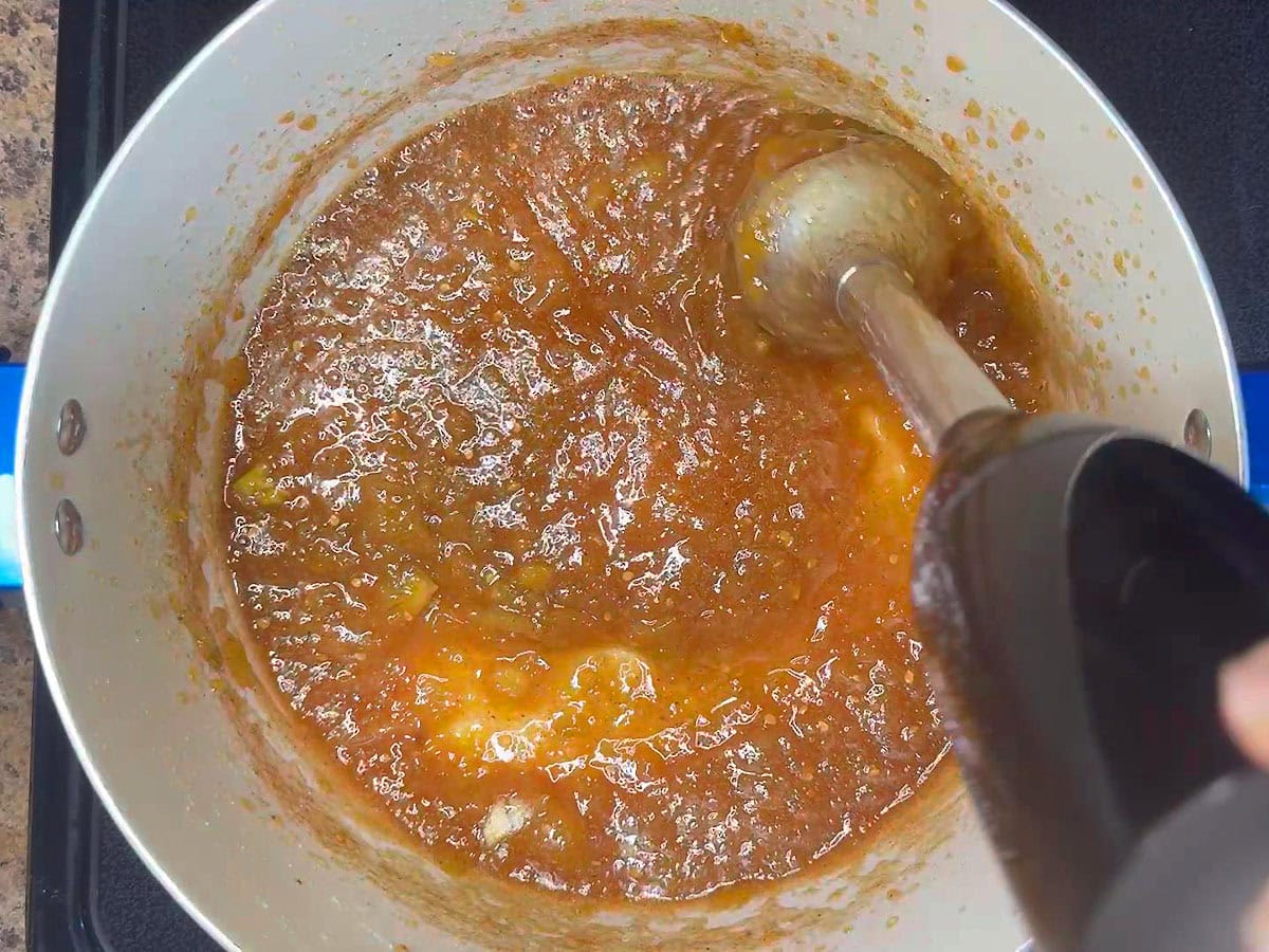 Using an immersion blender to blend the jam.