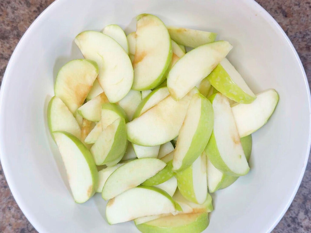 Sliced apples in a large mixing bowl.