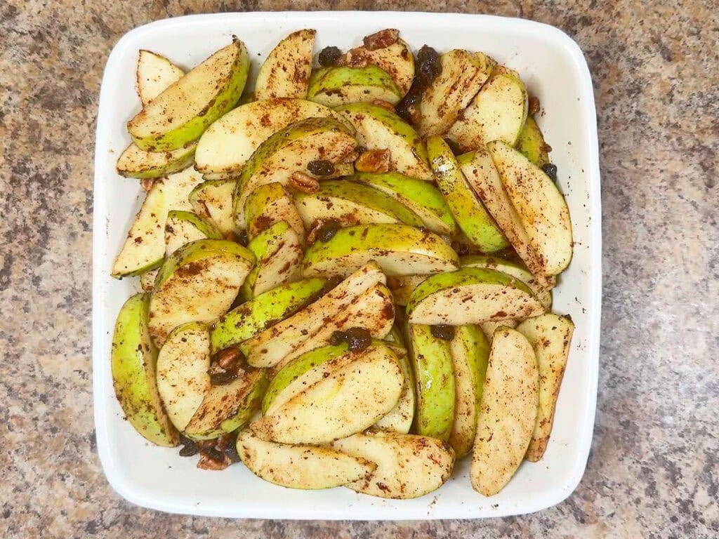 Apples in a square baking dish after baking for 30 minutes and the foil has been removed.