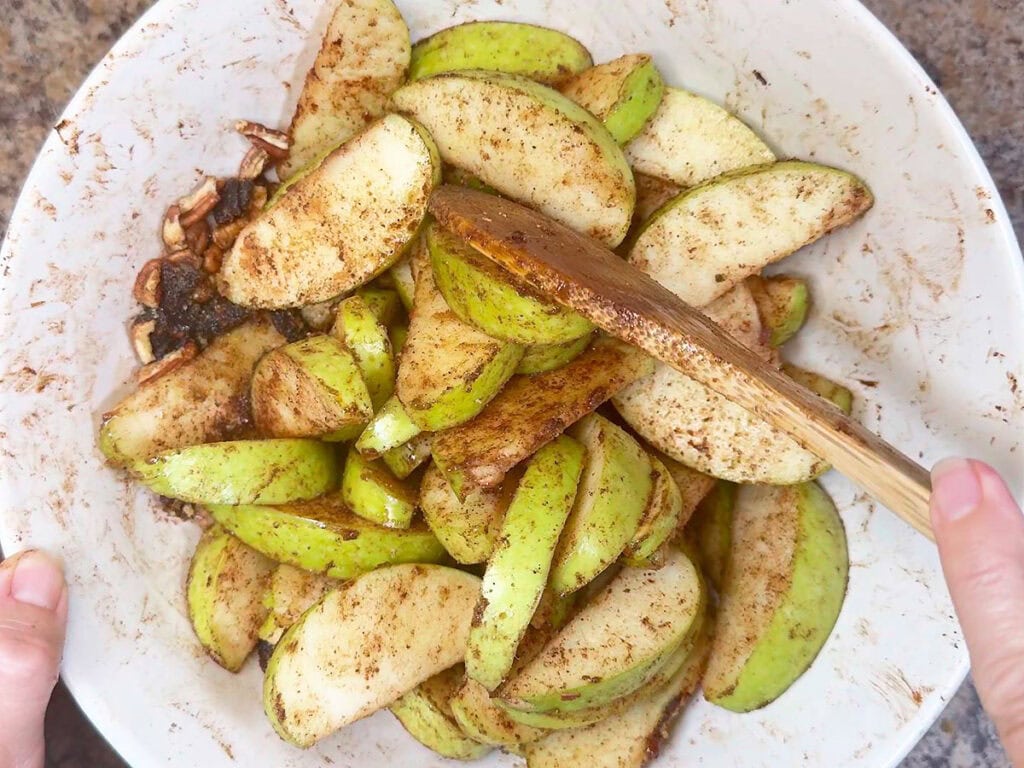 Mixing the apples, sugar, and spices in a large mixing room.