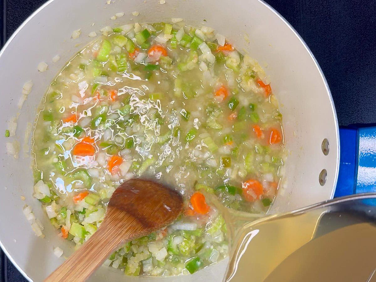 Adding shrimp stock to the vegetables.