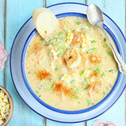 Bowl of shrimp and corn bisque garnished with corn kernels and toasted bread.