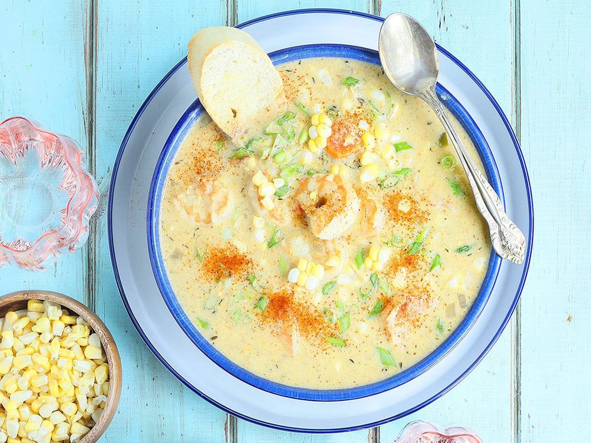 Bowl of shrimp and corn bisque garnished with corn kernels and toasted bread.