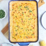 Baked cheesy corn casserole garnished with parsley in a rectangular baking dish.