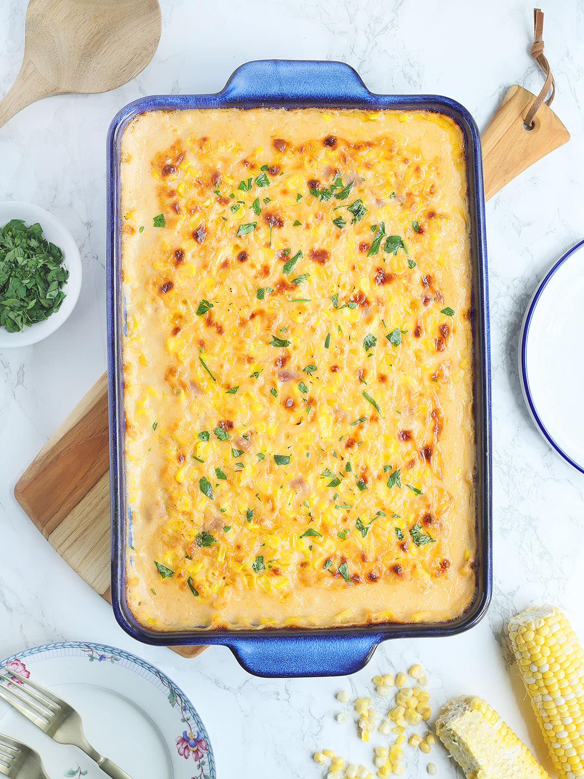 Baked cheesy corn casserole garnished with parsley in a rectangular baking dish.