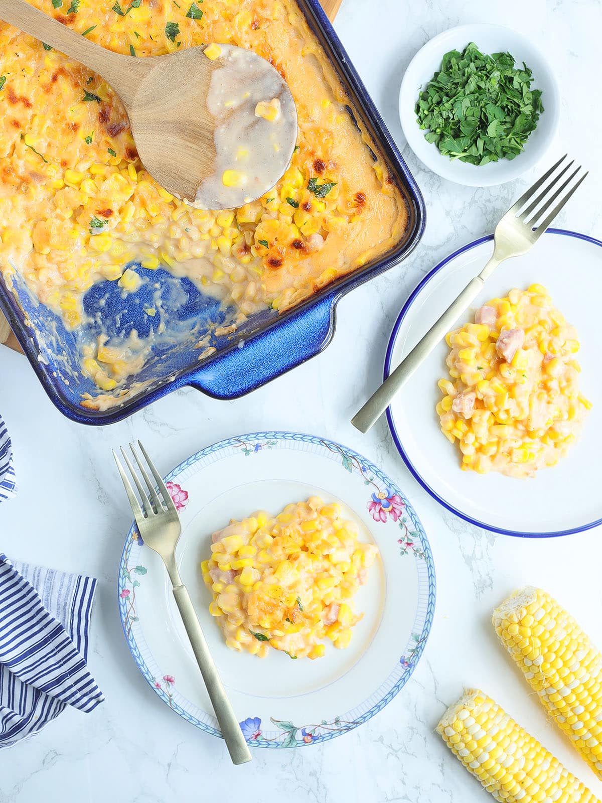 Serving of cheesy corn casserole on a plate with a fork.