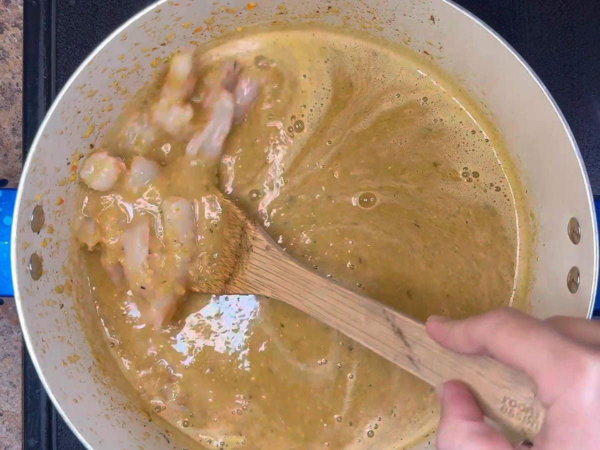 Adding the shrimp and heavy cream to the pot with the pureed bisque base.