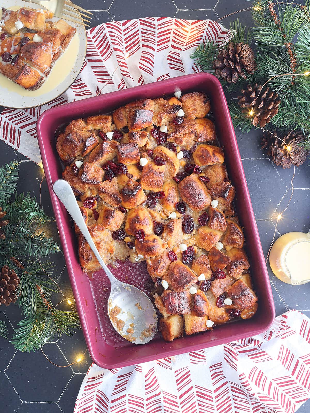 Pan of white chocolate cranberry bread pudding with a slice removed.
