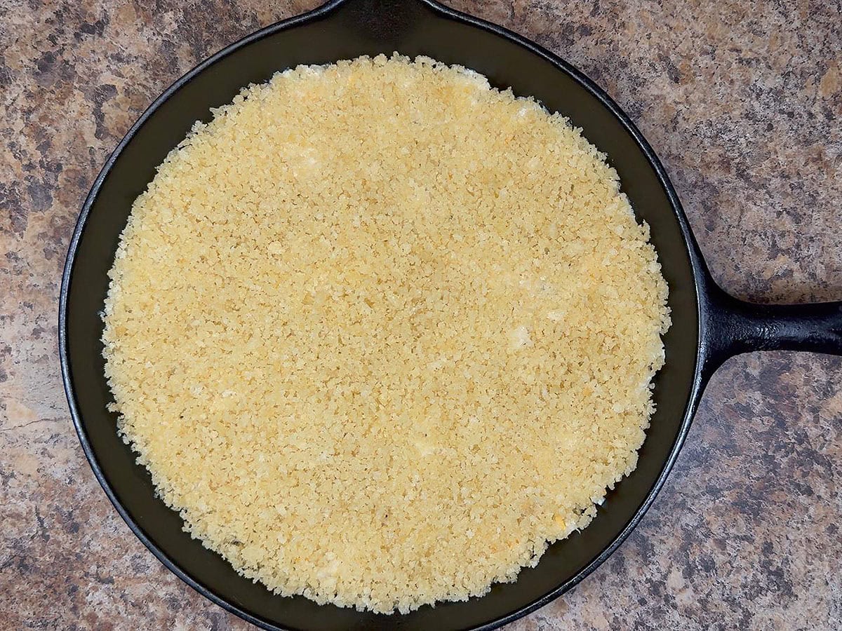 Mashed cauliflower spread into an even layer on the bottom of a greased cast iron skillet and topped with Panko breadcrumbs.