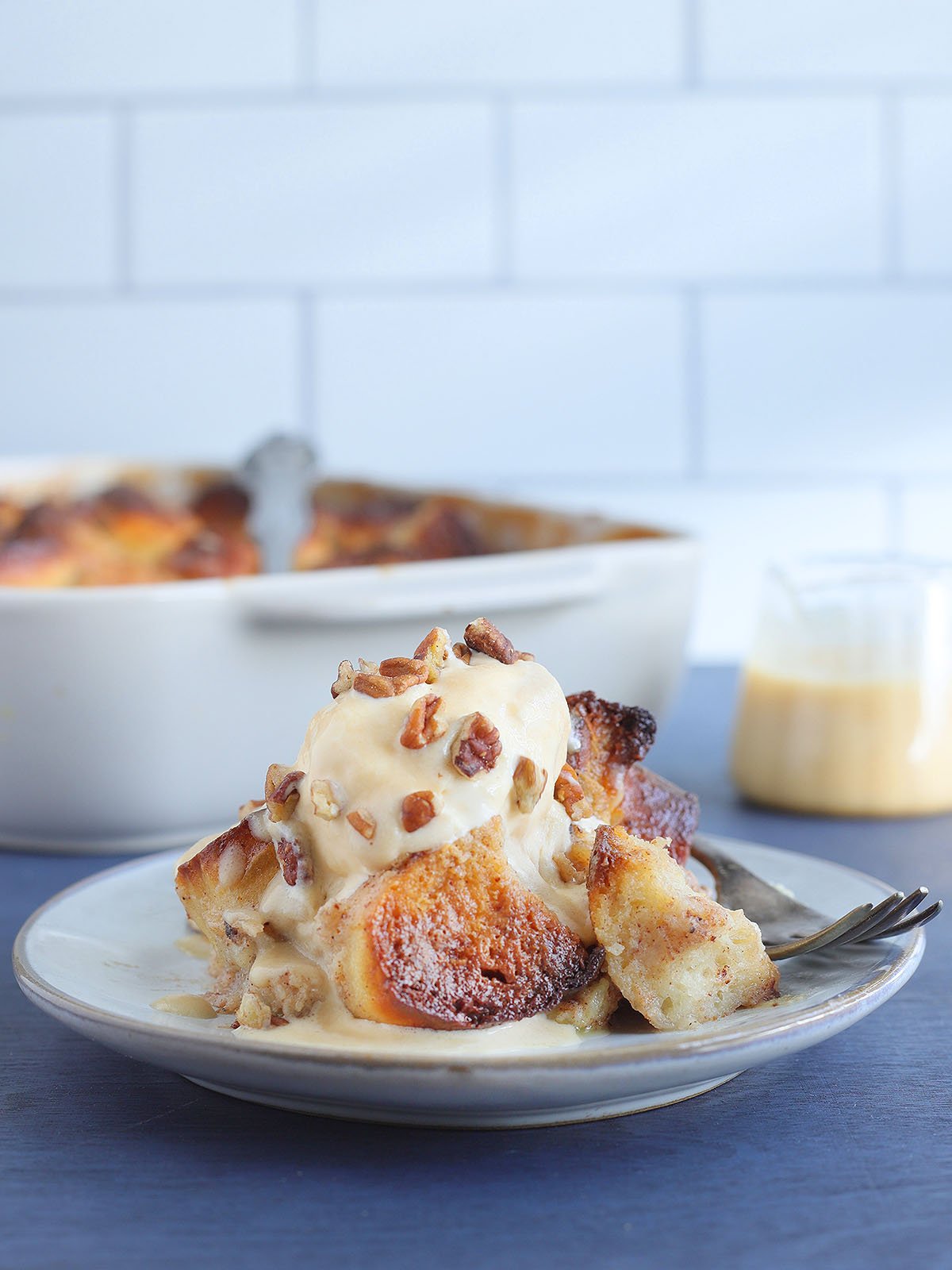 Sliced of pina colada pineapple raising bread pudding topped with ice cream, chopped pecans, and rum sauce.