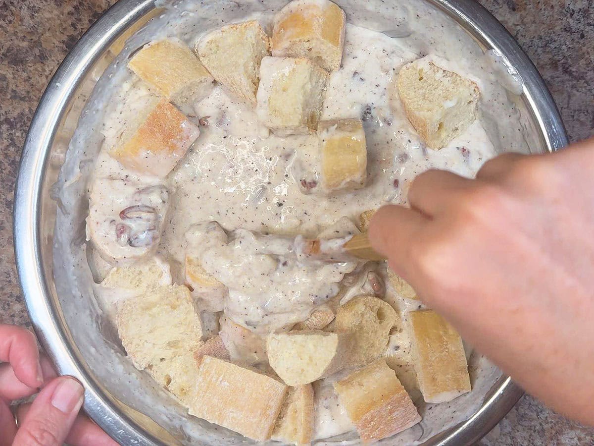 Stirring the cubed bread into the custard base.