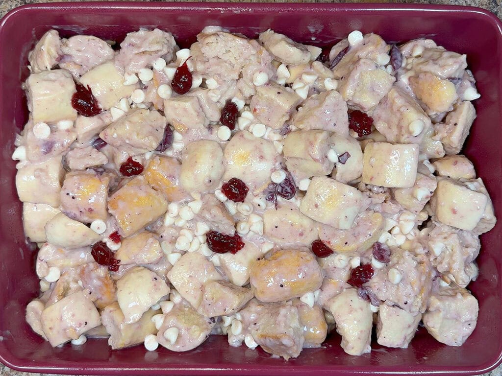 White chocolate cranberry bread pudding spread into the bottom of a greased baking pan.