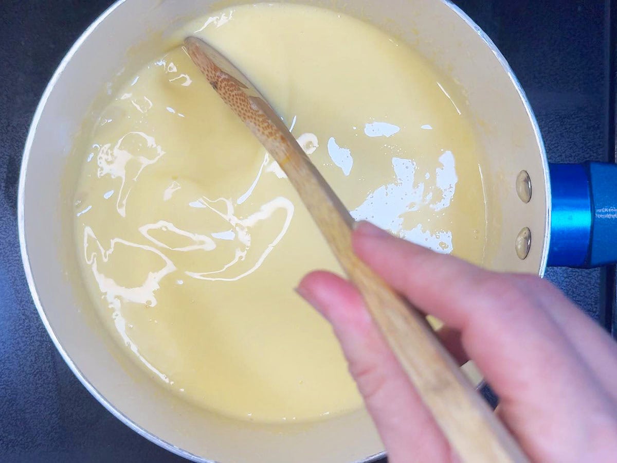 Stirring the cream and tempered egg yolks until thick.