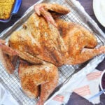 Smoked spatchcocked turkey resting on a rack on a foil lined baking sheet.