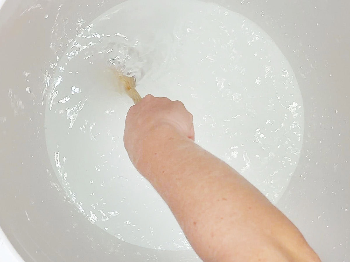 Stirring kosher salt into water in a cooler until the salt dissolved.