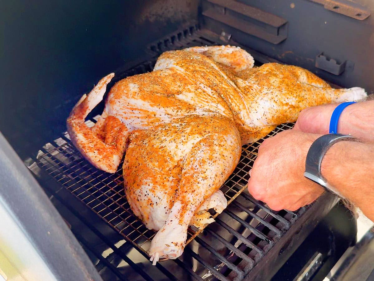 Placing the whole turkey in the smoker.