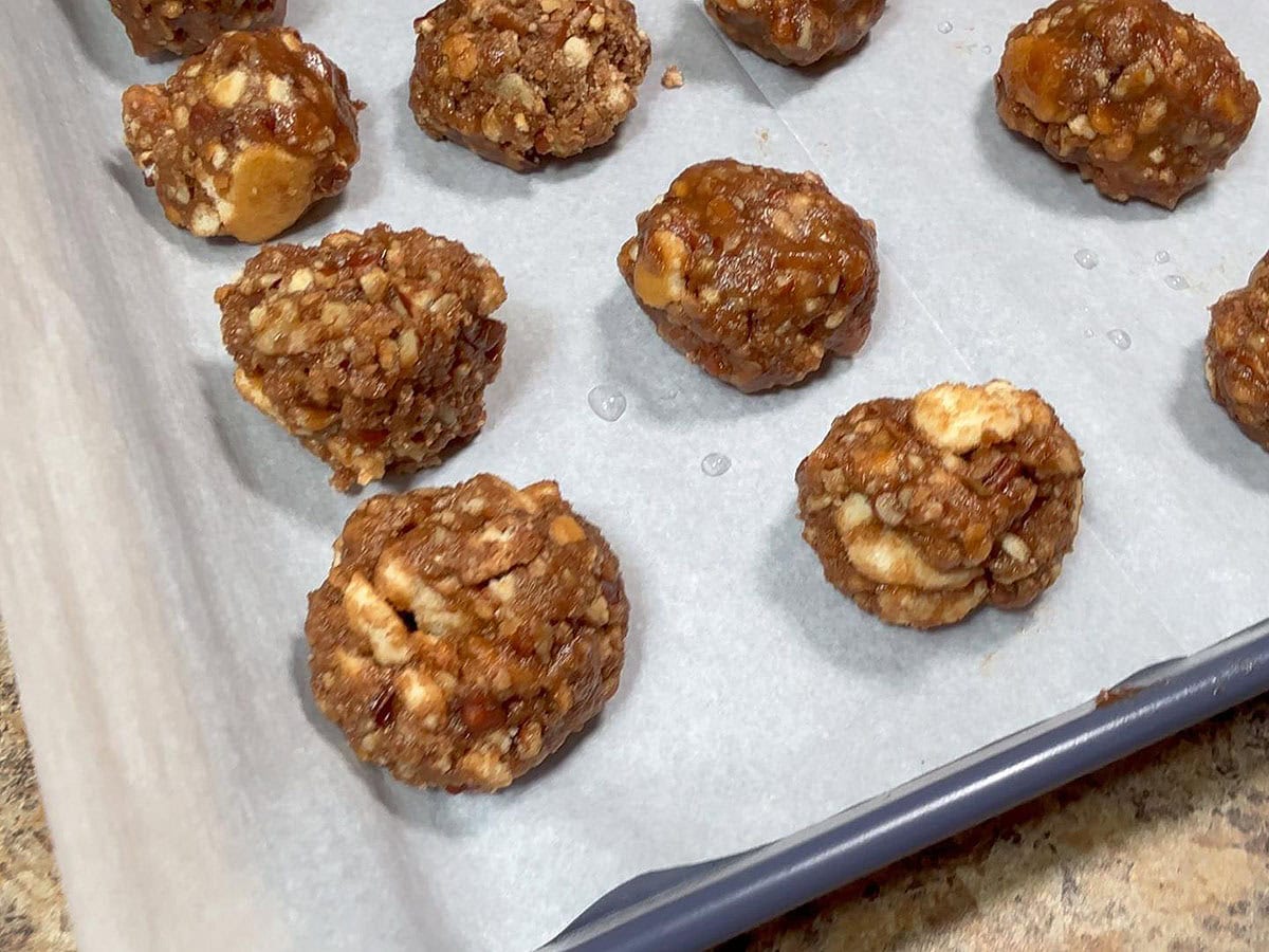 Formed bourbon balls on a parchment paper lined baking sheet.
