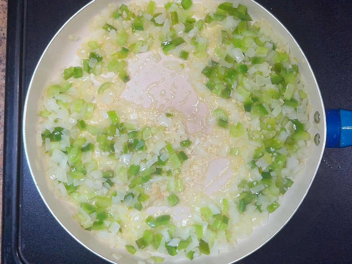 Sauteing diced onions, celery, bell pepper and garlic in butter in a large saucepan.