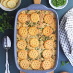 Scalloped oysters topped with Ritz crackers and parsley in a casserole dish.