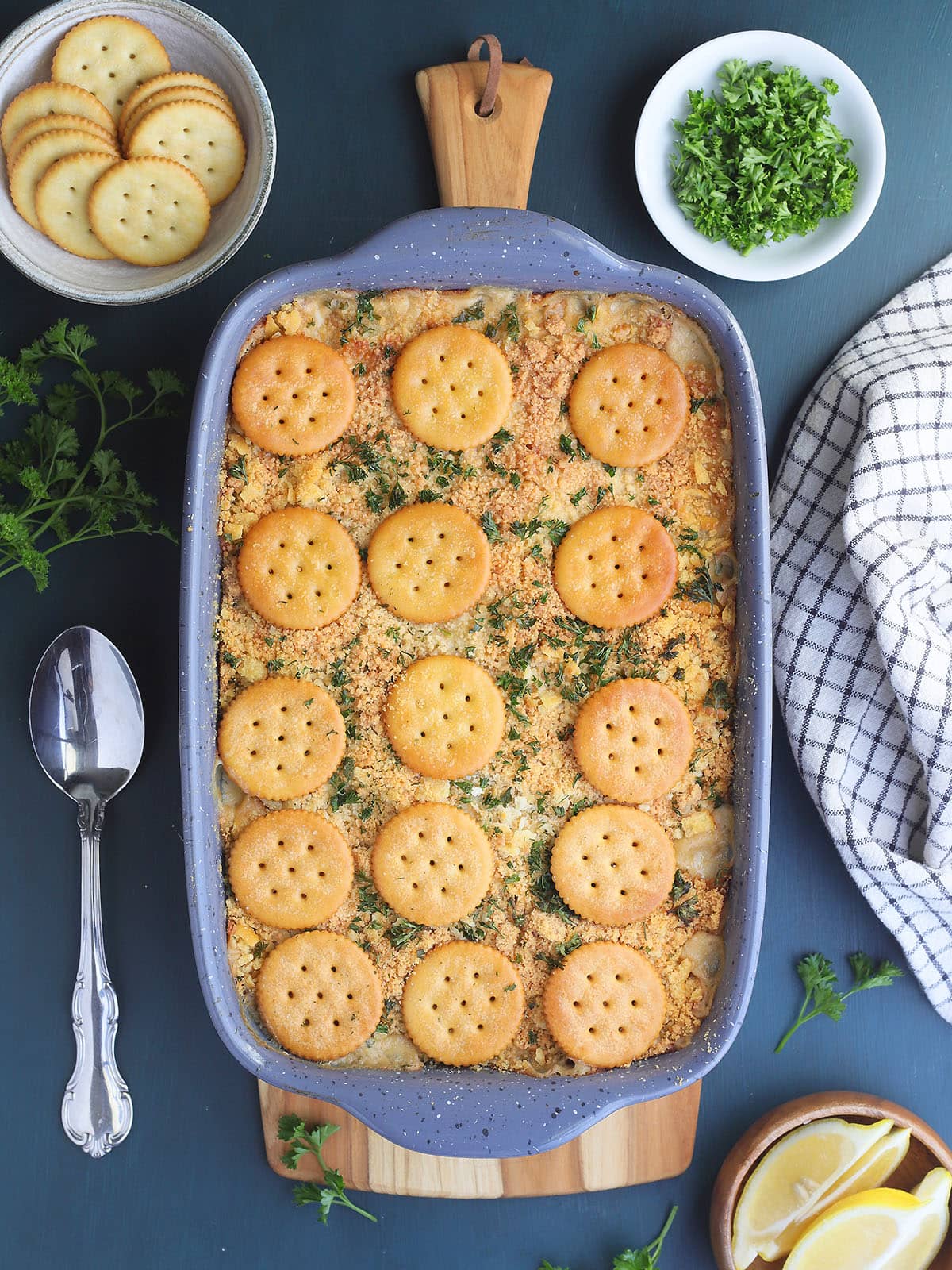 Scalloped oysters topped with Ritz crackers and parsley in a casserole dish.